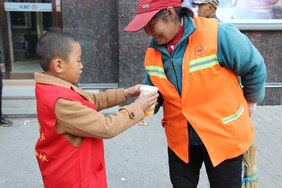 小志愿者为正在辛勤工作的环卫工人送上一杯热气腾腾的小米粥